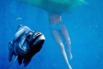 A piranha floats near a woman's body underwater in Piranha (1978)