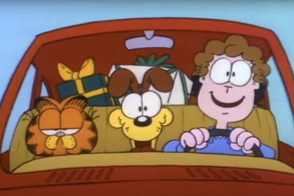 Garfield and Odie sit in a car next to Jon who is driving with a backseat full of presents.