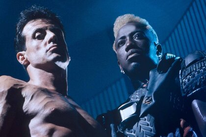 John Spartan (Sylvester Stallone) is shirtless while blonde Simon Phoenix (Wesley Snipes) wear armor in Demolition Man (1993).