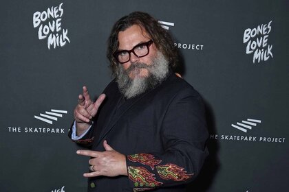 Jack Black throws up hand signs while wearing glasses and a black shirt.