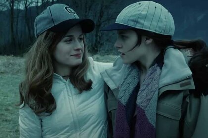 Esme Cullen (Elizabeth Reaser) and Bella Swan (Kristen Stewart) hug while wearing baseball caps in Twilight (2008).
