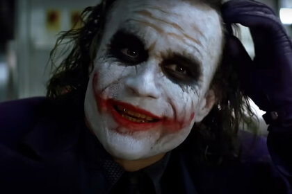 The Joker (Heath Ledger) smiles in his signature face makeup in The Dark Knight (2008).
