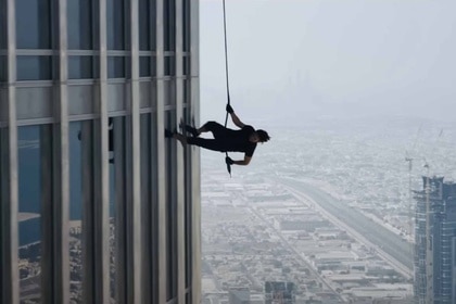 A cable-suspended Ethan Hunt (Tom Cruise) runs on the side of the building in Mission: Impossible – Ghost Protocol (2011).