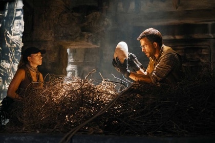 Zora Bennett (Scarlett Johansson) watches Dr. Henry Loomis (Jonathan Bailey) hold a giant egg in a giant nest in Jurassic World Rebirth (2025).