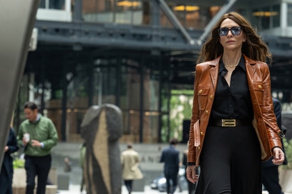 Kathryn St Jean wears a brown leather jacket in the city in Black Bag