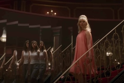 Eloise (Thomasin McKenzie) appears in the reflection of a mirror as Sandie (Anya Taylor-Joy) walks down stairs in Last Night in Soho (2021).
