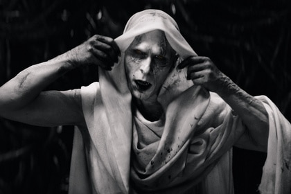 Gorr (Christian Bale) grabs his hood to remove it in Thor: Love and Thunder (2022).