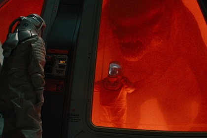 A D-Rex approaches a person in a hazmat suit in Jurassic World Rebirth (2025)
