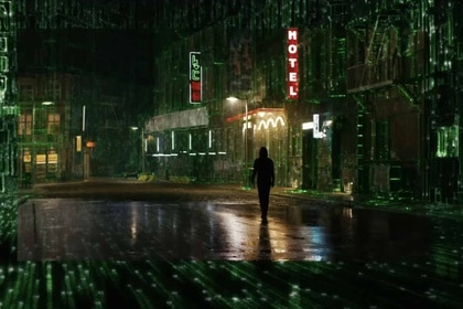 Neo (Keanu Reeves) walks through a city that glows with green matrix numbers in The Matrix Resurrections (2021).