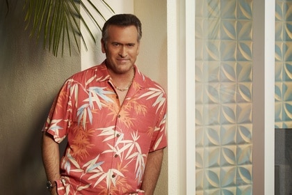 Sam Axe (Bruce Campbell) poses in a peach colored Hawaiian shirt on Burn Notice Season 7.