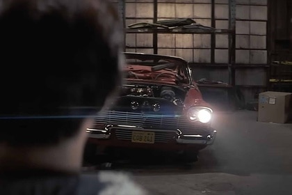 A man watches Christine turn her headlights on in Christine (1983).