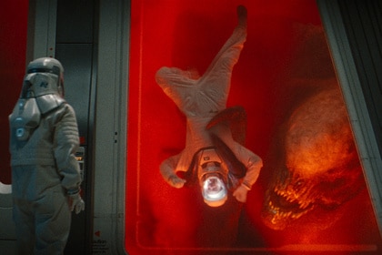 D-Rex mauls someone as a scientist watches from behind protective glass in Jurassic World Rebirth (2025).