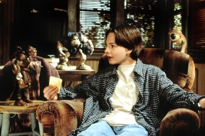 Alan Abernathy (Gregory Smith) sits on a sofa while speak with small Gorgonites on Small Soldiers (1998).