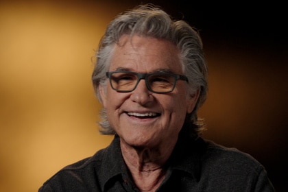 Kurt Russell, smiling, being interviewed for The Thing Expanded.