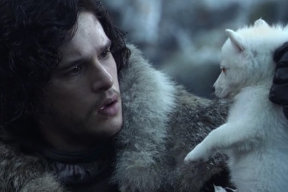 Kit Harington as Jon Snow holding up his wolf puppy in the Game of Thrones pilot.