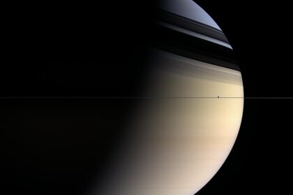 To scale, Saturn's rings are thinner than paper. This Cassini image shows them edge-on, with the moon Enceladus seen right in the ring plane as well.
