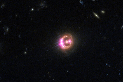 The quasar RX J1131-1231 appears as a series of bright dots on a ring around the fuzzy elliptical galaxy in the center due to gravitational lensing. This is a Hubble image (red, green, and blue) combined with Chandra which sees X-rays (displayed as pink).