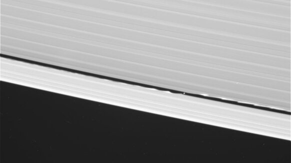 Cassini took this wide-angle shot of Daphnis around the same time as the narrow angle one. Note how far the waves go around the rings. Saturn is to the upper right. This is a raw image, so there are some blemishes that aren't real objects. Credit: NASA/JP