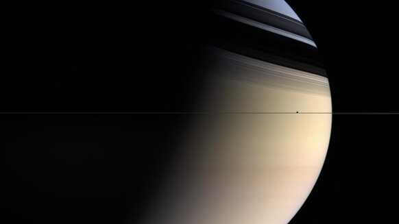 To scale, Saturn's rings are thinner than paper. This Cassini image shows them edge-on, with the moon Enceladus seen right in the ring plane as well.