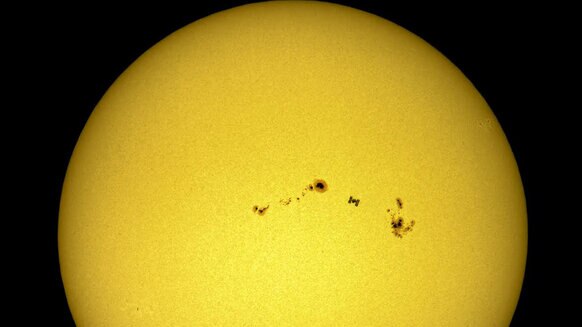 ISS transiting the Sun between two huge sunspot groups. Credit: Dani Caxete