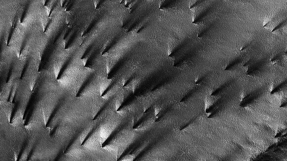 HiRISE camera view of strange fan-like sprays of dark material erupting from the ground near the south pole of Mars. Credit: NASA/JPL/UArizona