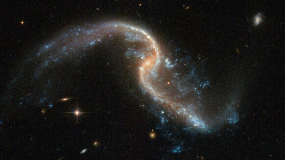 Arp 256N in more detail. Note the tidal tails and bright blue spots indicating star formation sites. Credit: ESA/Hubble, NASA