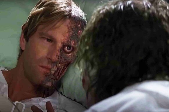 Two-Face (Aaron Eckhart) glares at The Joker in The Dark Knight (2008).