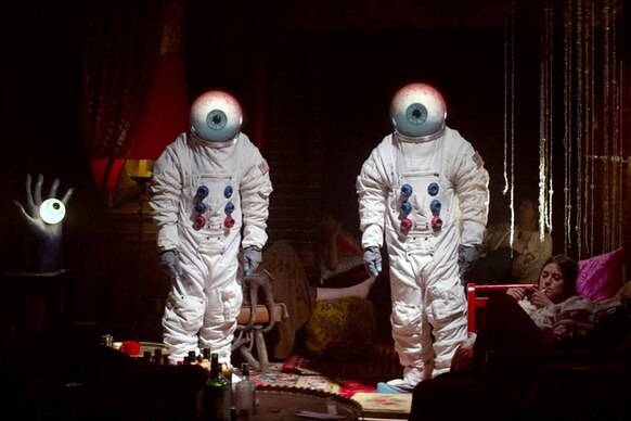 Two astronauts with eyeball heads stand in Moonwalkers (2016).