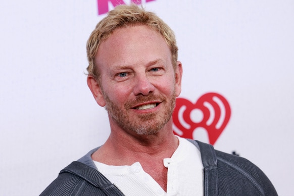 Ian Ziering smiles in front of an iHeartRadio backdrop.