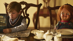 Chucky sits at a dining table with Henry Collins (Callum Vinson) in Chucky 301.