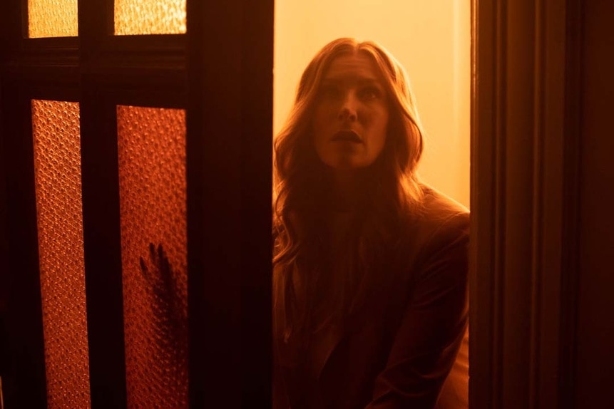 Susan Ireland (Sarah Levy) is illuminated in orange as she walks through a door in SurrealEstate 203.