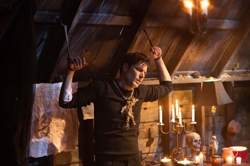 Luke Roman's (Tim Rozon) wrists are tied up near an altar as he wears a straw necklace in SurrealEstate 204.