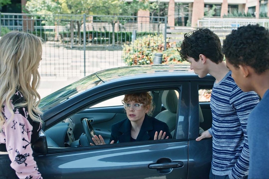 (l-r)  Lexy Cross (Alyvia Alyn Lind),  Jake Wheeler (Zachary Arthur), and Devon Evans (Bjorgvin Arnarson) look at Miss Fairchild (Annie Briggs) who sits in a car in Chucky 302 -- “Let the Right One In”
