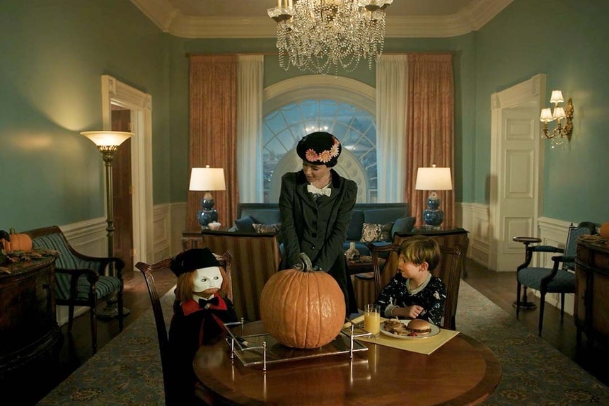 (l-r) Chucky,  Annie Gilpin (Sarah Sherman), Henry Collins (Callum Vinson) sit at a table with a large pumpkin in Chucky 304.