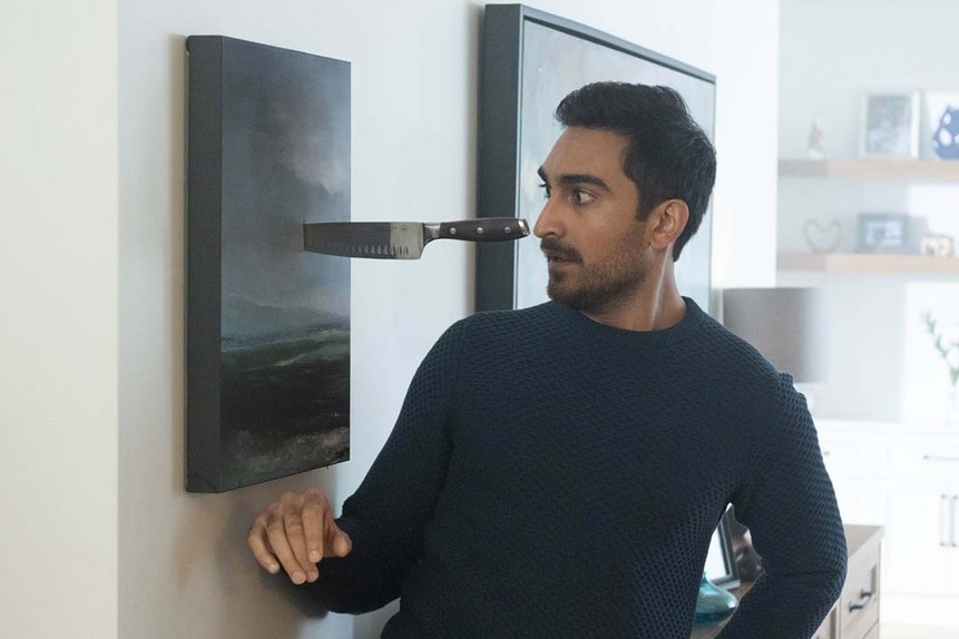 Nasir (Daniel Malik) looks in shock at a knife embedded in a wall that was meant for his head in SurrealEstate 209.