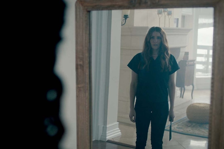 A woman appears in a mirror holding a butchers knife in SurrealEstate 208.