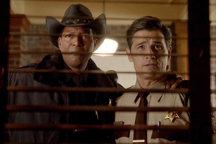Sheriff Mike Thompson and Joseph Rainier look through blinds in Resident Alien Episode 301.