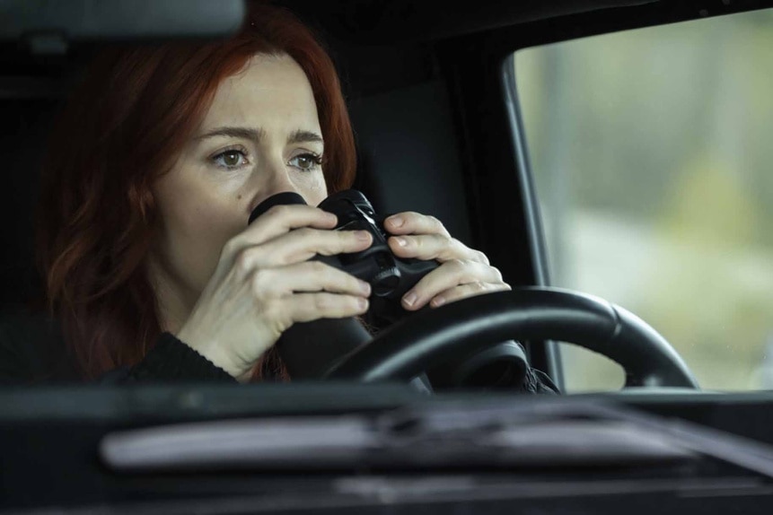 D'Arcy Bloom holds binoculars in a car on Resident Alien Episode 308.