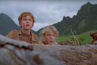 Joseph Mazzello as Tim Murphy and Ariana Richards as Lex Murphy hiding behind a rock in Jurassic Park (1993)