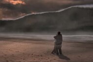 A still image of a big wave approaching two people embracing on a beach in Deep Impact (1998)