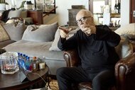 John Carpenter sits on a sofa and points his fingers in John Carpenter's Suburban Screams 106