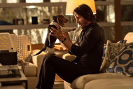 John Wick (Keanu Reeves) sits on a couch while holding a beagle puppy in John Wick (2014)