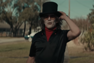 The Grabber (Ethan Hawke) holds a black top hat on his head while wearing all black with a red undershirt in The Black Phone (2021).