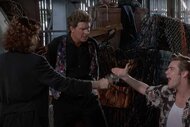 Ace Ventura (Jim Carrey) (R) points at Lui-Même (Dan Marino) while a woman holds them at gunpoint in Ace Ventura: Pet Detective (1994).