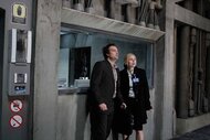 Radnor (David Hewlett) and Angela (Christina Cole) appear distressed wearing businesswear in a concrete building in Time Machine: Rise of the Morlocks (2011).