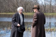 Albert Einstein (Tom Conti) and J. Robert Oppenheimer (Cillian Murphy) speak near a pond in Oppenheimer (2023).