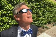 Bill Nye wears eclipse glasses.