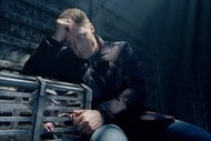Harry Vanderspeigle rests on a cage holding Baby Alien within on Resident Alien Episode 308.