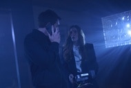 Luke Roman (Tim Rozon) speaks on the phone while Susan Ireland (Sarah Levy) holds a machine on SurrealEstate Episode 301.