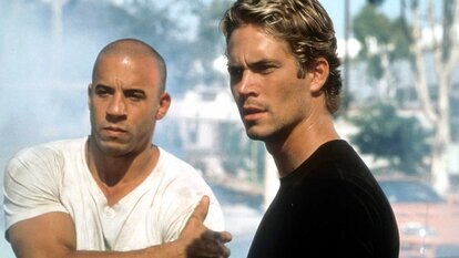 Vin Diesel and Paul Walker stand next to each other in a scene from The Fast And The Furious